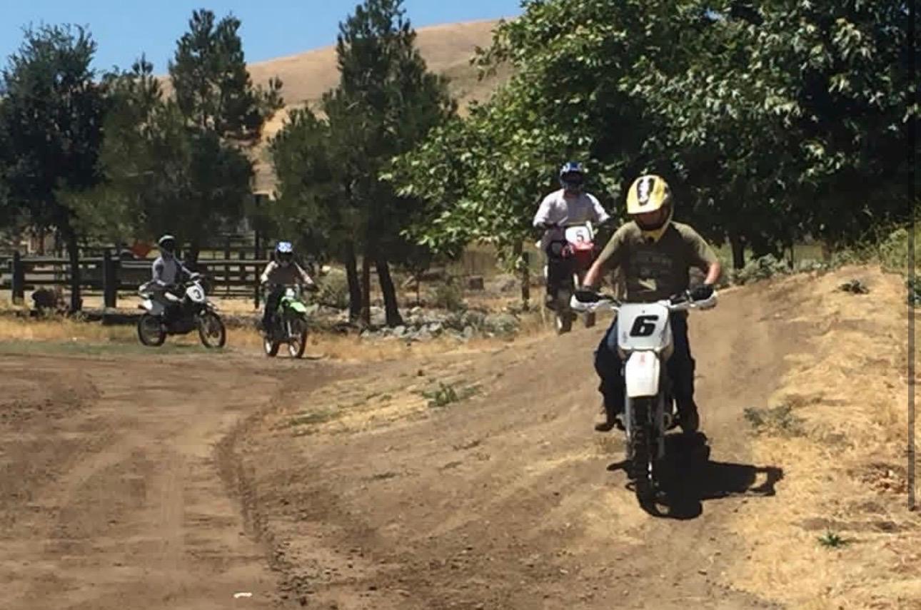 A rider leading a group around a curve on the dirt bike training trail