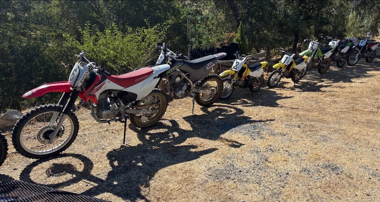 A lineup of Learn Dirt Bikes rental motorcycles beside the training area
