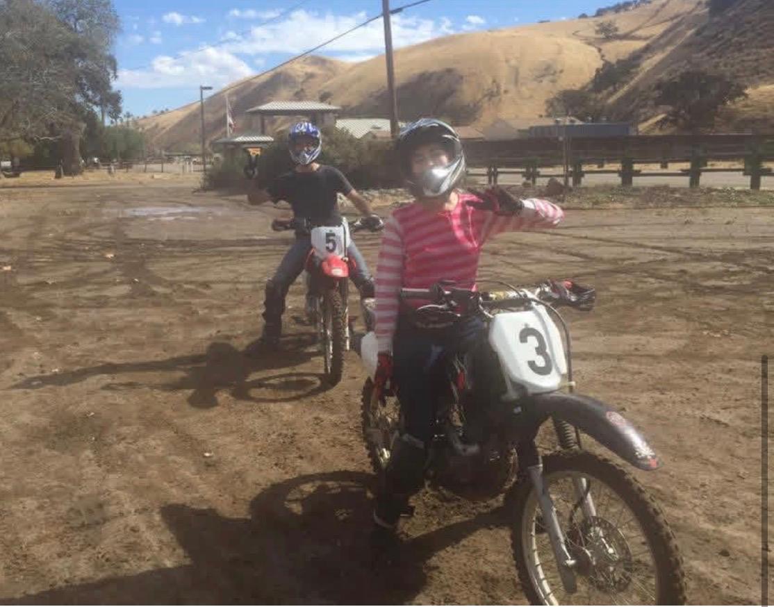 Two dirt bike riders waving from the training course