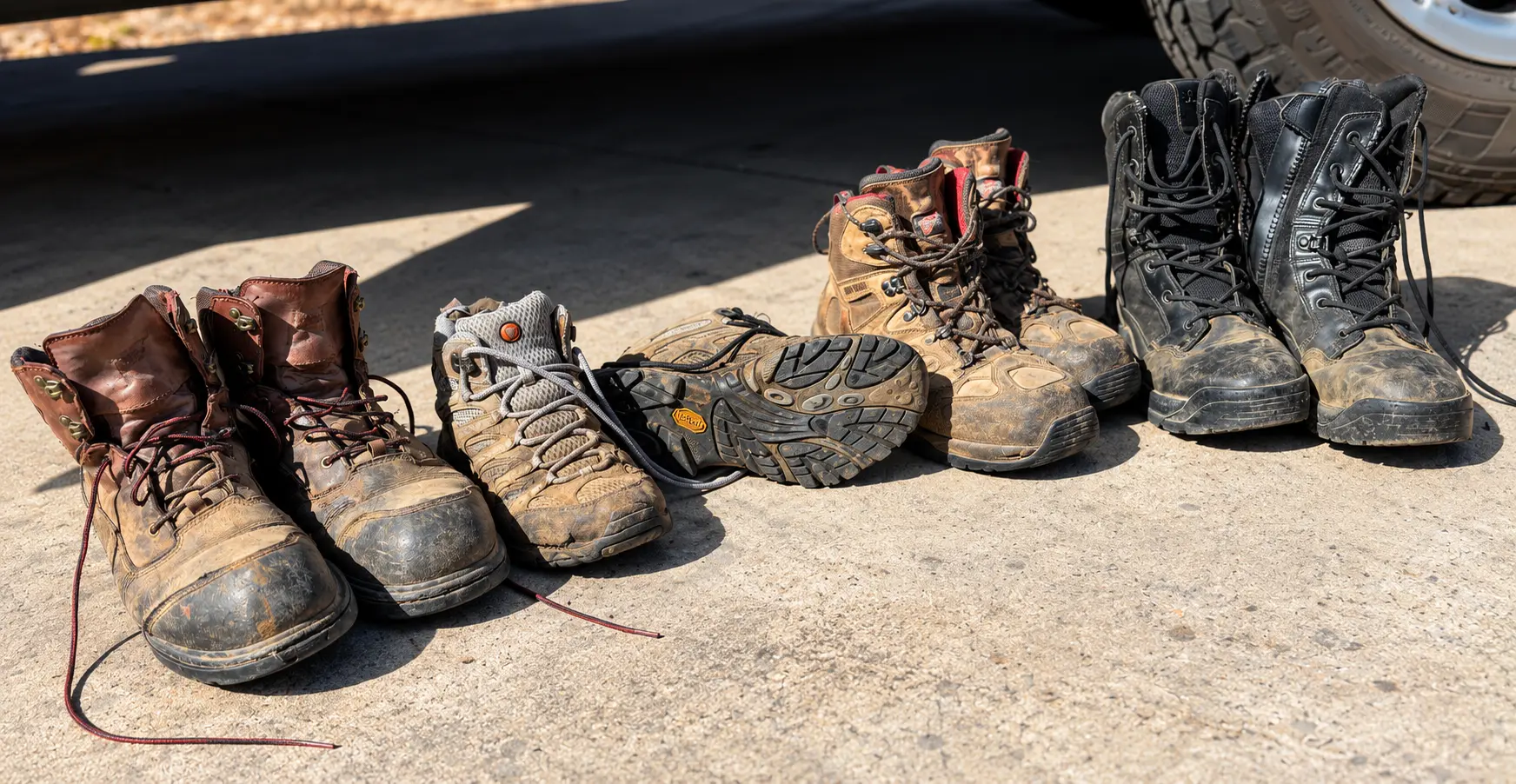 Several pairs of sturdy, lace-up protective boots lined up on concrete